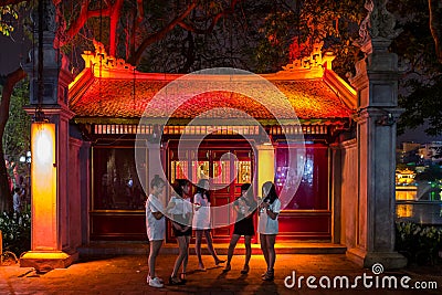 Hanoi, Vietnam - April 15, 2018: Young girls chat near Cau The Huc in Hanoi. Editorial Stock Photo