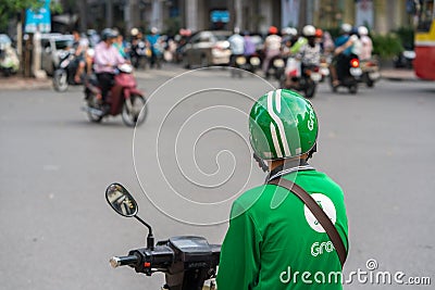 Hanoi, Vietnam - July 7, 2017: Grab motorbike driver waiting for customer on Ba Trieu street. Entered Vietnam in 2014, Grab growin Editorial Stock Photo