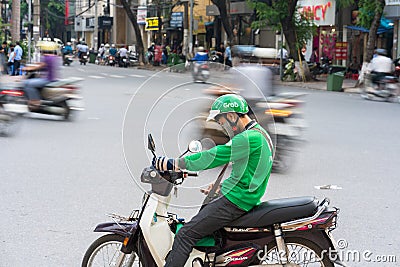 Hanoi, Vietnam - July 7, 2017: Grab motorbike driver waiting for customer on Ba Trieu street. Entered Vietnam in 2014, Grab growin Editorial Stock Photo