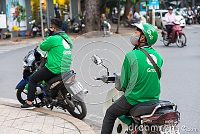 Hanoi, Vietnam - July 7, 2017: Grab motorbike driver waiting for customer on Ba Trieu street. Entered Vietnam in 2014, Grab growin Editorial Stock Photo