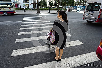 Hanoi, Vietnam - Oct 19, 2016: Mother with a baby stroller crossing the street in Minh Khai. Vehicles running on street. Editorial Stock Photo