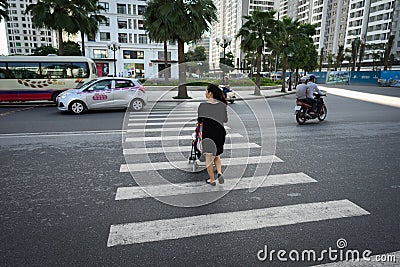 Hanoi, Vietnam - Oct 19, 2016: Mother with a baby stroller crossing the street in Minh Khai. Vehicles running on street. Editorial Stock Photo