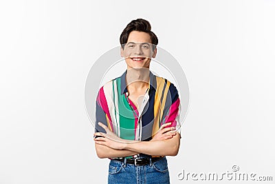 Hansome smiling gay man looking happy, standing over white background in summer outfit Stock Photo