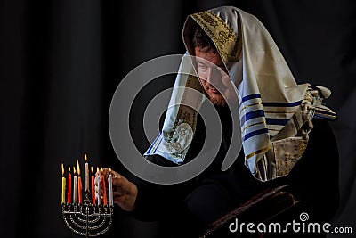 Hanukkah, a Jewish celebration. Candles burning in the menorah, man in the background. Stock Photo