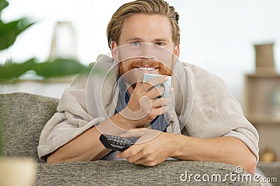 Happ man watching tv while holding cuppa Stock Photo