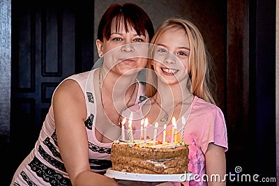 The happiest family.Mom with her cute daughter holds a cake for her birthday Stock Photo