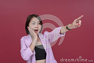 A happily surprised asian woman gushes while pointing to the right. Covering her mouth, recognizing someone well known, Stock Photo