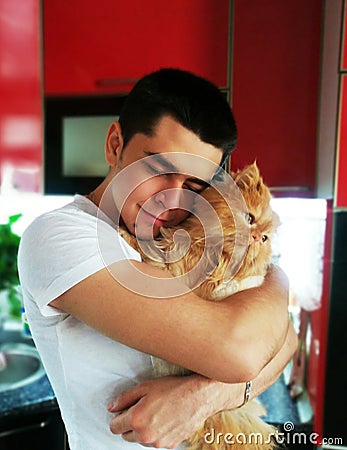 Happiness. Cat with Young Man. Orange Persian Cat. Lover Man, Hugging and Cuddling his Happy Domestic Cat Pet. Love to the animals Stock Photo