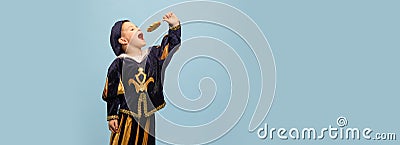 Cute little charming boy in costume of medieval pageboy, little prince with big lollipop over light blue background Stock Photo