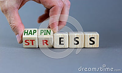 Happiness instead of stress. Businessman turns a cube and changes the word `stress` to `happiness`. Beautiful grey background. Stock Photo