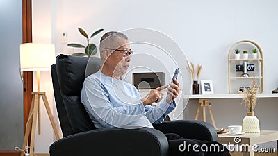 Happiness of wellness elderly asian man with white hairs sitting on sofa using mobile phone Stock Photo