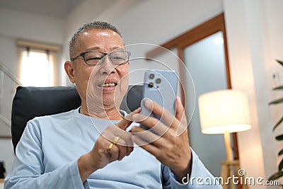 Happiness of wellness elderly asian man with white hairs sitting on sofa using mobile phone Stock Photo