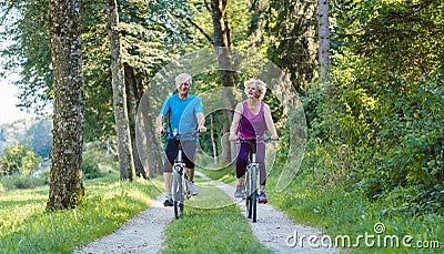 Happy and active senior couple riding bicycles outdoors in the p Stock Photo