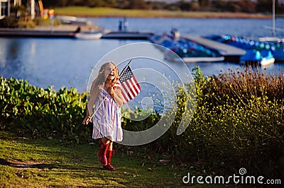 Happy adorable little girl smiling and waving American flag outs Stock Photo