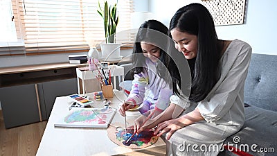 Happy siblings enjoy painting pictures together in living room. Stock Photo