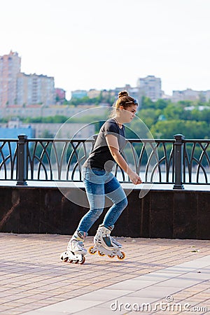 A girl rides roller skates in a city Park in summer Stock Photo