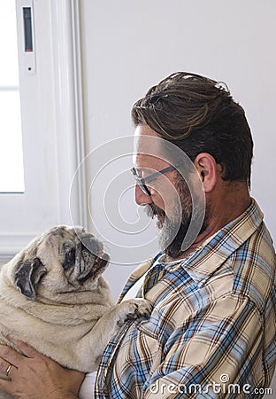 Happy adult hipster man hug and play with his old best friend dog pug at home - people and lovely animals life indoor Stock Photo