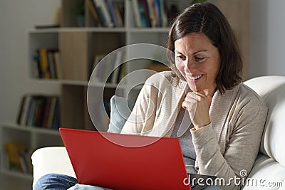 Happy adult lady streaming content on laptop at night at home Stock Photo