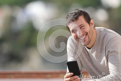 Happy adult man holding smart phone looks at camera Stock Photo