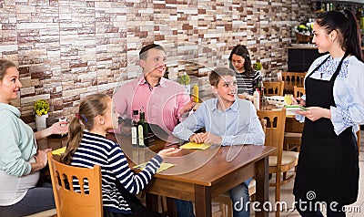 Happy adults with children are giving order to cheerful waitress Stock Photo