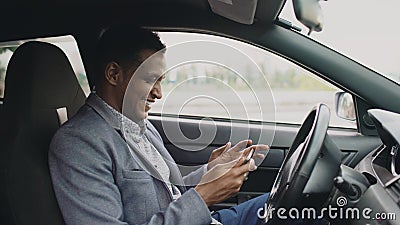 Happy african american businessman surfing social media on his tablet computer sitting inside his car Stock Photo