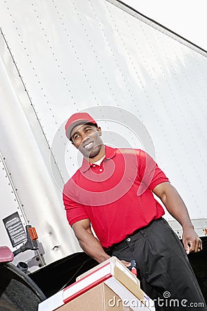 Happy African American delivery man pushing handtruck Stock Photo