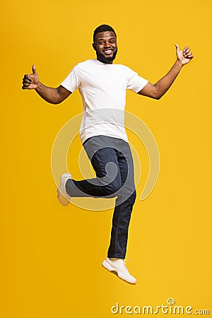 Happy african american man jumping and showing thumbs up Stock Photo