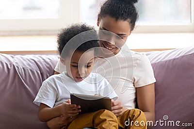 Happy african american mother sitting with son on couch. Stock Photo