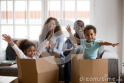 Happy african parents and kids playing in boxes enjoy relocation Stock Photo