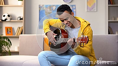 Happy African-American teenager playing guitar, enjoying favorite hobby, leisure Stock Photo