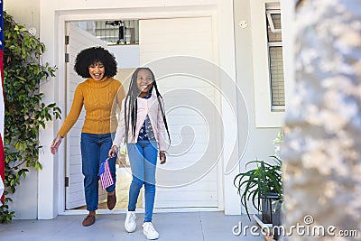 Happy african american wife and daughter welcoming male soldier outdoors with usa flag, copy space Stock Photo
