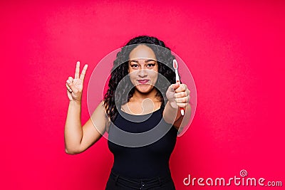 Happy African American woman brushes teeth. Dental hygiene concept. Isolated on red background. Stock Photo