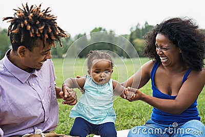 Happy African family having fun together in public park - Black father and mother enjoying time with their daughter Stock Photo