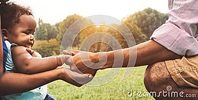 Happy African family having fun together in public park - Black father and mother holding hand with their daughter Stock Photo