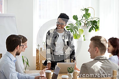 Happy african manager leading team meeting talking to colleagues Stock Photo