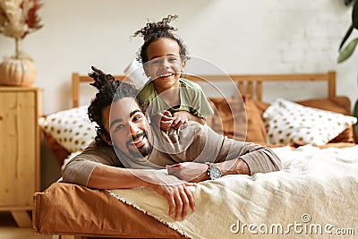 Happy afro american family father and cute little son relaxing at home in bed Stock Photo