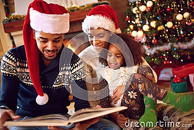 Happy afro American family read a book at fireplace on Christmas Stock Photo