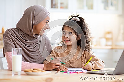 Happy Arab Family Mom And Little Daughter Drawing Together In Kitchen Stock Photo