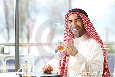 Happy arab man holding a cup of tea looking at camera Stock Photo