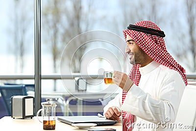 Happy arab man looking away holding a tea cup Stock Photo