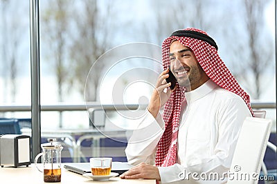 Happy arab man talking on phone in a coffee shop Stock Photo