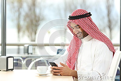 Happy arab man using a smart phone in a coffee shop Stock Photo