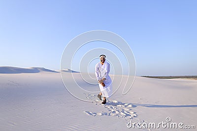 Happy Arab man walks in middle of white desert and enjoys life o Stock Photo