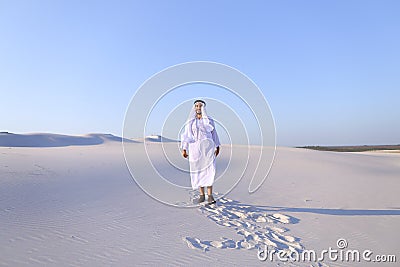 Happy Arab man walks in middle of white desert and enjoys life o Stock Photo