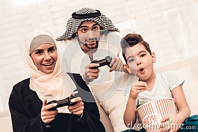 Happy Arabian Family Playing on Console at Home. Stock Photo