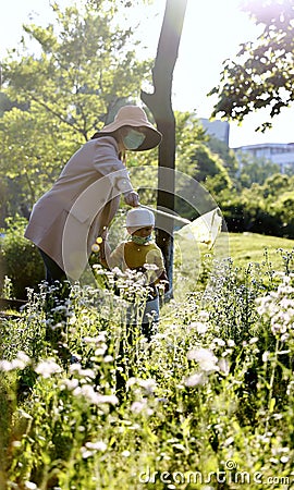 Happy Asia Chinese little boy toddler child wear mask play with his mother mom have fun hold string net catch insects childhood Stock Photo