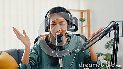 Happy asia girl record a podcast with headphones and microphone look at camera talk and take a rest in her room. Female podcaster Stock Photo