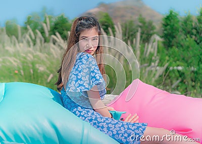 Happy beautiful woman portrait on a picnic pillow in a green nature field for happiness freedom lifestyle concept Stock Photo