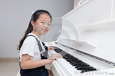 Happy Asian Chinese little girl playing classical piano at home Stock Photo