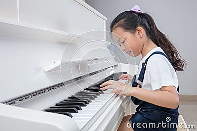 Happy Asian Chinese little girl playing classical piano at home Stock Photo